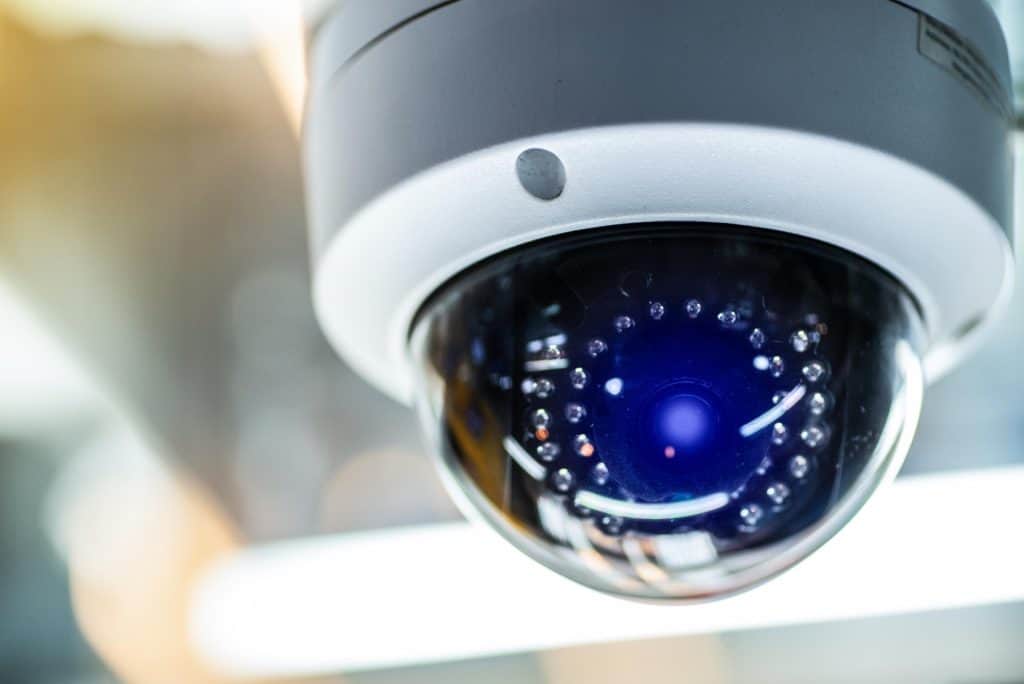 Close-up of a dome-shaped security camera with a reflective surface and visible LED lights, mounted indoors.